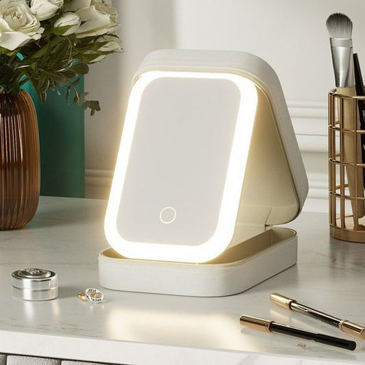 Lighted makeup mirror on a desk with beauty products and flowers in the background